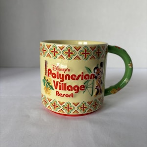 May include: A ceramic mug featuring the text "Disney's Polynesian Village Resort" in red and yellow. The mug has a green handle and a decorative pattern in red, yellow, and green. Mickey Mouse and Minnie Mouse are depicted on the side.