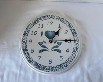Vintage CORELLE wall clock with a white face with blue heart and floral designs and a speckled blue border. B4