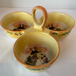 May include: A three-sectioned serving dish with a handle. The dish is yellow with a brown rim and a painted rooster design in each bowl. Green and yellow floral accents are painted around the rim of each bowl.