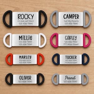 May include: Eight rectangular metal pet ID tags with silicone loops on each side in black, gray, white, pink, red, and navy blue. Each tag features a custom name and phone number printed in black text, including phrases like I'm lost, call Mom.