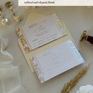 Pu&ograve; includere: Due biglietti d'invito con stampa in lamina d'oro e argento su carta bianca strutturata. I biglietti sono in una busta con un motivo floreale. Il testo sui biglietti recita "Kindly Respond by November 22nd".