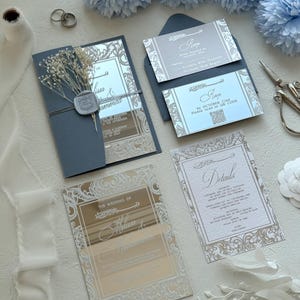 Pu&ograve; includere: Elegante suite di inviti di nozze con biglietti in acrilico a specchio e intricati disegni floreali. La suite include biglietti RSVP, biglietti di dettaglio e un invito piegato, il tutto in tonalit&agrave; argento e blu. Elementi decorativi includono fiori secchi e un sigillo di cera.