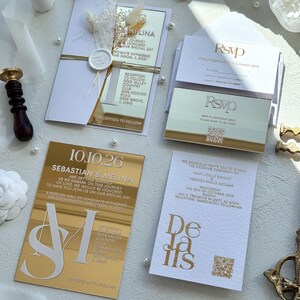 Puede incluir: Elegante conjunto de invitaciones de boda con papeler&iacute;a dorada y blanca. Incluye tarjetas de invitaci&oacute;n, tarjetas de confirmaci&oacute;n de asistencia y tarjetas de detalles. Las invitaciones tienen detalles dorados espejados y adornos florales y de perlas.