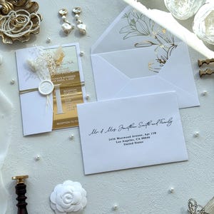 Puede incluir: Elegante conjunto de invitaciones de boda con una tarjeta de invitaci&oacute;n con detalles dorados, flores secas y un sobre blanco con dise&ntilde;o floral. Incluye detalles de perlas y un sello de cera.
