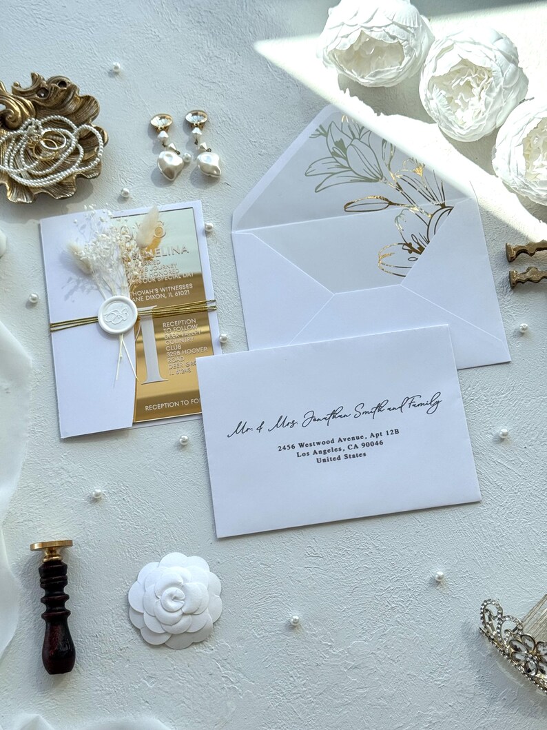 Puede incluir: Elegante conjunto de invitaciones de boda con una tarjeta de invitaci&oacute;n con detalles dorados, flores secas y un sobre blanco con dise&ntilde;o floral. Incluye detalles de perlas y un sello de cera.