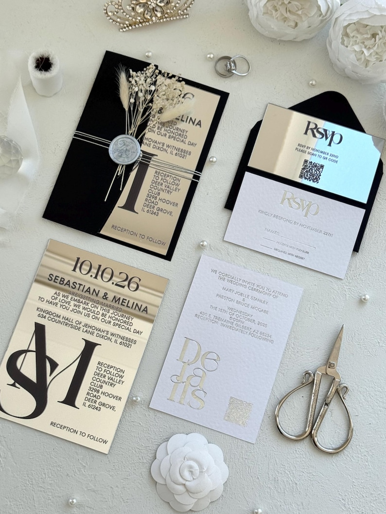 May include: Elegant wedding invitation suite featuring black and gold cards with event details. Includes an RSVP card, details card, and a card with the couple's names and date. Embellished with pearls, dried flowers, and a silver crown.