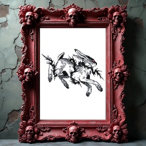 Op de afbeelding: Een rode fotolijst met schedelaccenten. De lijst omringt een gepixelde zwart-wit afbeelding van twee konijnen. De lijst is versierd en heeft schedels in elke hoek en in het midden.