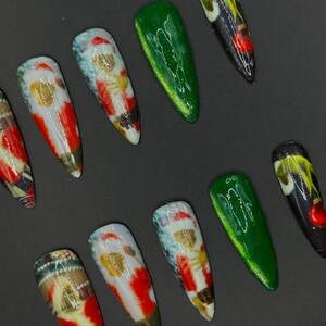 May include: A collection of ten artificial nails. The nails showcase diverse designs, including Santa Claus, green glitter, and abstract art. The nails are long and pointed, with a glossy finish. The background is a plain black.