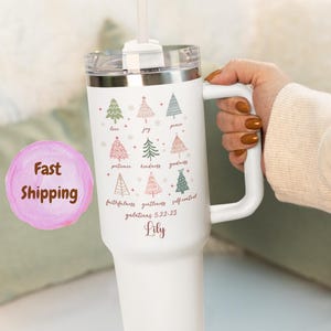 May include: White insulated tumbler with a handle, featuring a Christmas tree design and the words "love, joy, peace, patience, kindness, goodness, faithfulness, gentleness, self-control." The name "Lily" is printed below the text. Includes a clear lid and straw.