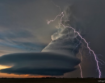 Könnte beinhalten: Ein dramatisches Bild einer dunklen, bedrohlichen Gewitterwolke, durch die ein Blitzschlag geht. Die Wolke hat die Form einer großen, flachen Scheibe, und der Blitz ist hellweiß vor dem dunklen Himmel.