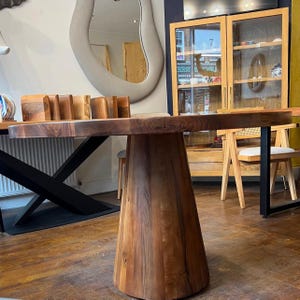 Puede incluir: Una mesa de comedor de madera maciza con tapa redonda y base c&oacute;nica. La mesa es de madera marr&oacute;n oscuro con vetas visibles. La mesa tiene aproximadamente 100 cm de di&aacute;metro y 76 cm de altura.