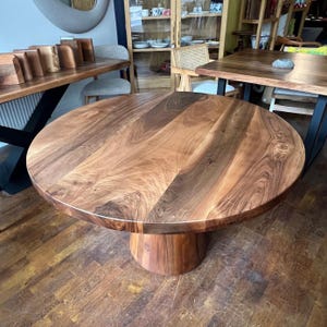Puede incluir: Una mesa de comedor redonda de madera con base de pedestal. La tapa es de color marr&oacute;n intenso con vetas de madera visibles. La mesa tiene aproximadamente 122 cm de di&aacute;metro.