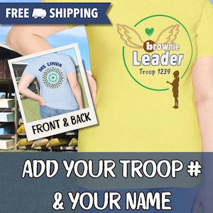 May include: Yellow t-shirt with a graphic for a Brownie troop leader. The design includes wings, a heart, and the words "brownie Leader Troop 1239." A smaller image shows the back of a light blue shirt with a circular design and the name "Ms. Linda."