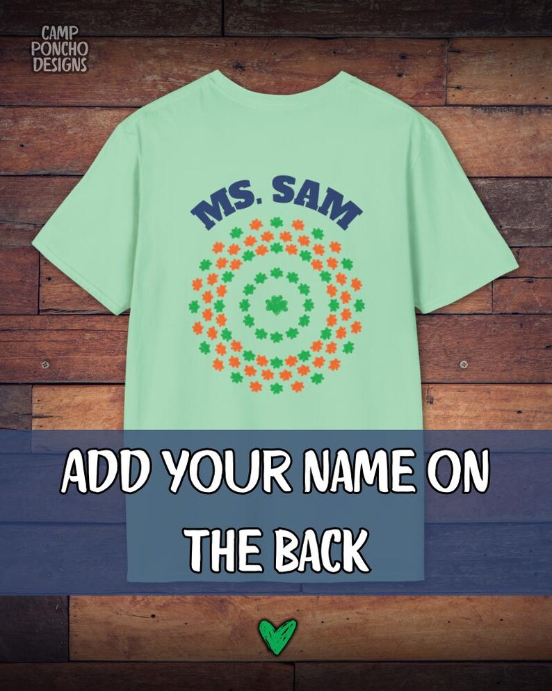 May include: A light green t-shirt with the text "MS. SAM" in blue. The shirt features a circular design of green and orange shamrocks. The text "ADD YOUR NAME ON THE BACK" is displayed below the design.