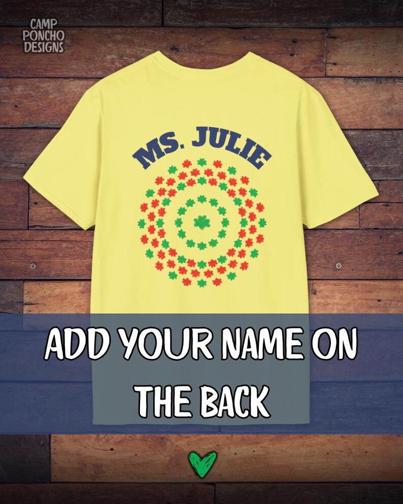 May include: Yellow t-shirt with the text "MS. JULIE" in blue, above a circular design of red and green shapes. The bottom of the shirt has the text "ADD YOUR NAME ON THE BACK". The Camp Poncho Designs logo is in the top left corner.