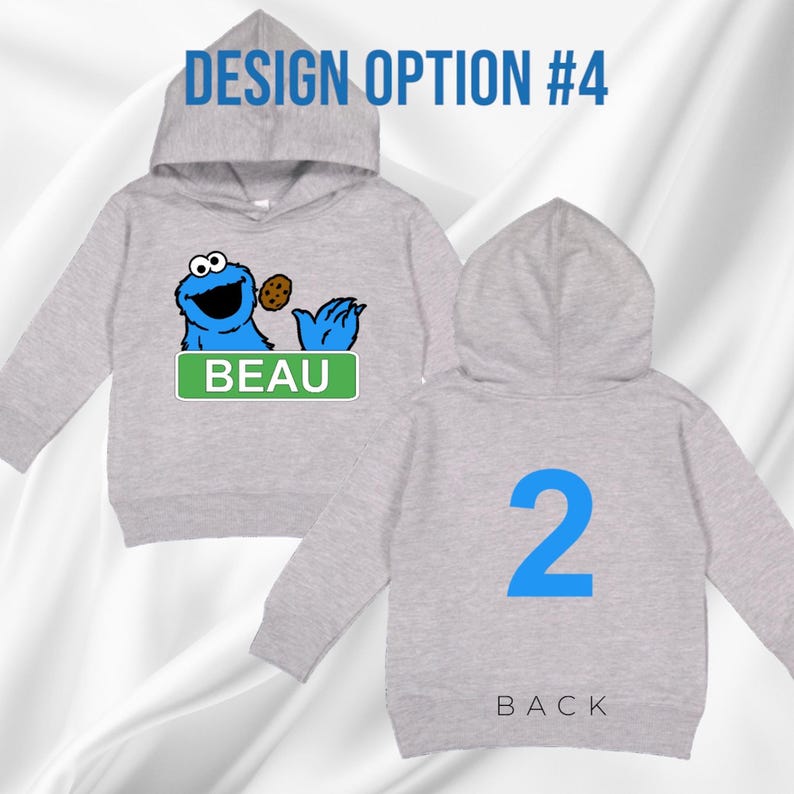 May include: A light grey hooded sweatshirt featuring a blue Cookie Monster graphic with a cookie and the name "BEAU" on a green sign. The back has a large blue number "2" and the word "BACK". The text "DESIGN OPTION #4" is at the top.