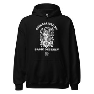 Puede incluir: Sudadera con capucha negra con un diseño gráfico. El diseño presenta una ilustración detallada de la cabeza de un perro rodeada de elementos florales y el texto "RADICALIZED BY BASIC DECENCY". La sudadera tiene una capucha con cordón y un bolsillo de canguro.