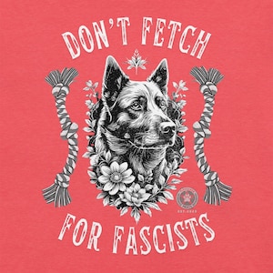 Może przedstawiać: Czerwona koszulka z grafiką przedstawiającą czarno-białą ilustrację psa otoczonego kwiatami. Tekst brzmi "DON'T FETCH FOR FASCISTS" w kolorze białym, z zabawkami z liny po obu stronach głowy psa.