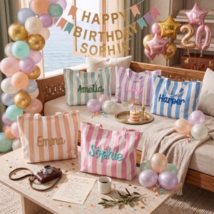 Peut inclure: Cinq sacs fourre-tout en toile ray&eacute;e avec des noms brod&eacute;s, dont Amelia, Lily, Harper, Emma et Sophie. Les sacs sont dispos&eacute;s sur une table en bois et un canap&eacute;, entour&eacute;s de ballons pastel, d'une banni&egrave;re d'anniversaire et d'un petit g&acirc;teau.