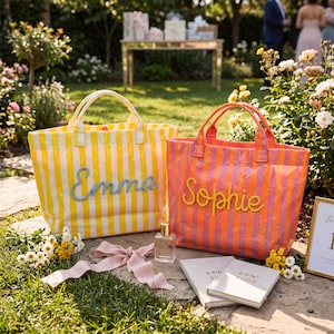 May include: Two rectangular tote bags with vertical stripes. The left bag is yellow and white with the name Emma in blue script. The right bag is orange and pink with the name Sophie in yellow script. Both bags feature two top handles.