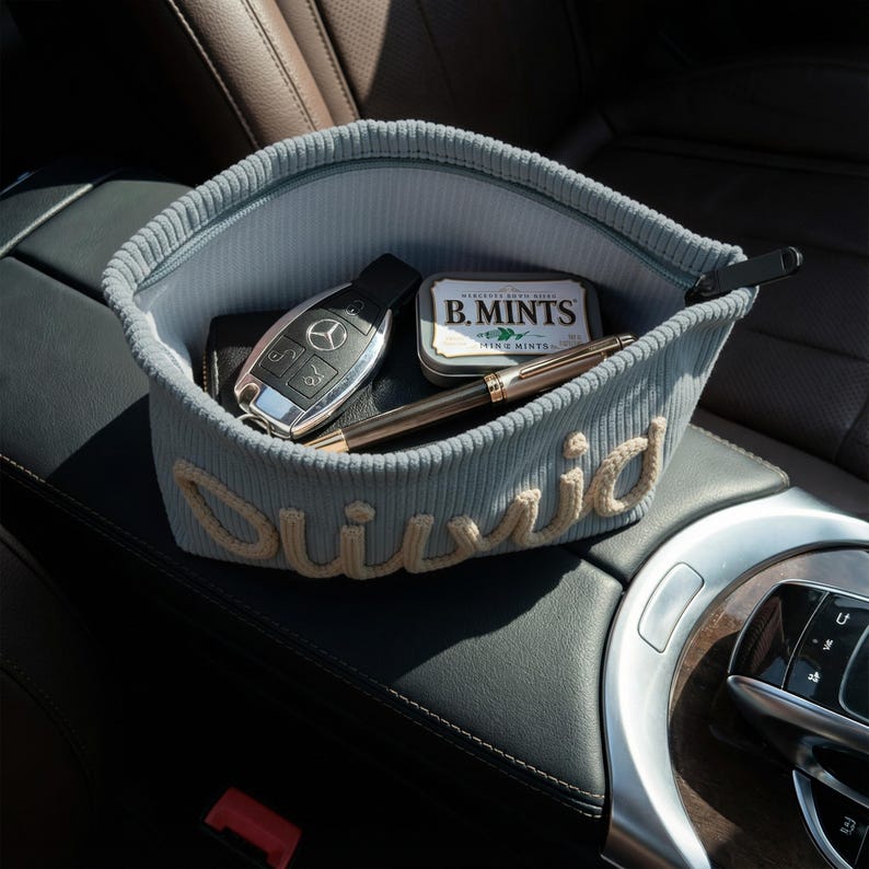 May include: A pale blue corduroy car tidy with a zip, holding a car key, wallet, pen, and a tin of B. Mints. The name "David" is embroidered on the front in cream yarn. Ideal for car storage.