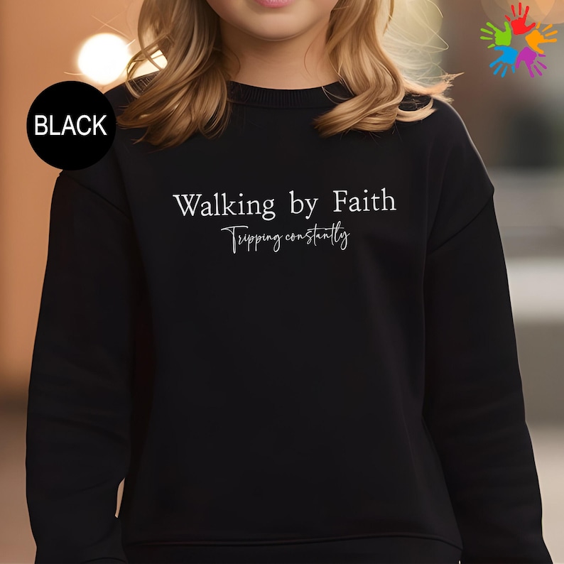 A person wearing a black sweater with the text "Walking by Faith" printed on it.