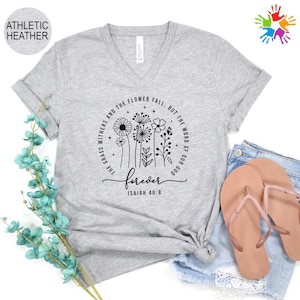 May include: A light gray V-neck t-shirt with the text "forever" and a floral design. The text "The grass withers and the flower fall, but the word of our God" is printed around the floral design. The text "Isaiah 40:8" is also printed on the shirt.