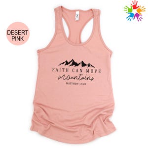 A pink tank top with a graphic design featuring mountains and the text "Faith can move mountains" printed on it.