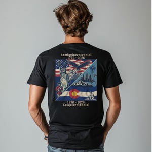Puede incluir: Una camiseta negra con un gráfico cuadrado en la espalda. El diseño incluye la Estatua de la Libertad, un águila, el Monte Rushmore, la bandera de Colorado y el texto Semiquincentennial 1776-2026 y 1876-2026 Sesquicentennial.
