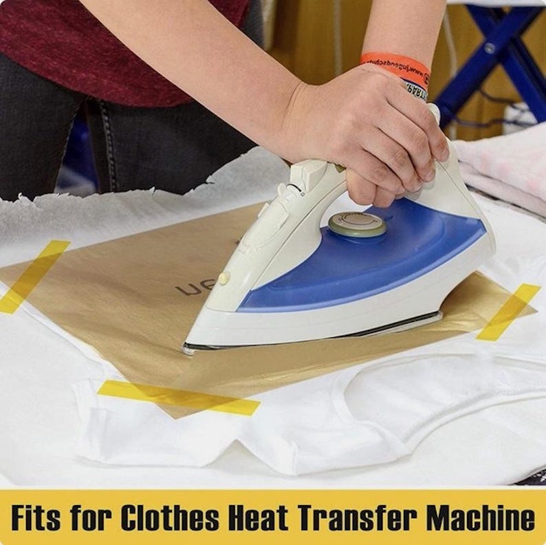 May include: A white and blue iron being used on a white t-shirt. A brown sheet of paper is placed between the iron and the shirt. The text "Fits for Clothes Heat Transfer Machine" is at the bottom of the image.