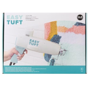 May include: The Easy Tuft tufting tool is a light blue and white handheld device shown on its product packaging. The box features the brand name We R Memory Keepers and displays a colorful tufted textile project with yellow, blue, and pink yarn.