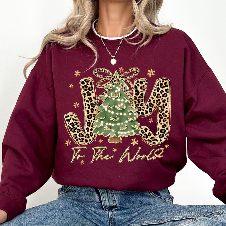 A woman wearing a burgundy sweatshirt with a Christmas tree design and the text "Joy To The World" printed on it.