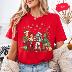 A woman wearing a red t-shirt with a cartoon character design of Toy Story characters.