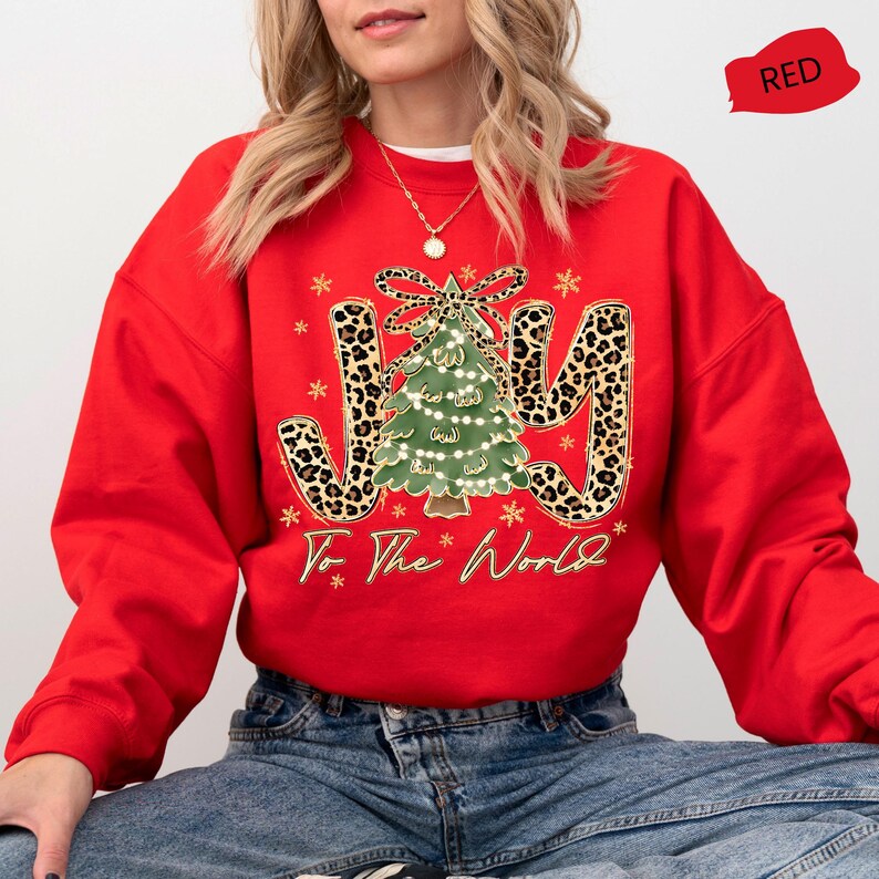 A woman wearing a red sweater with a Christmas tree design and the text "Joy to the World" printed on it.