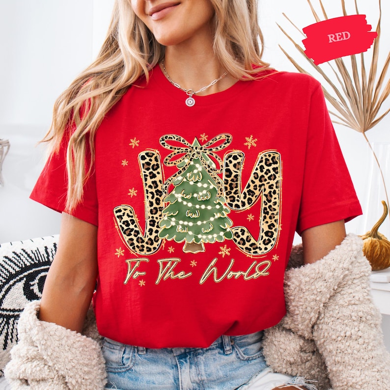 A woman wearing a red t-shirt with a Christmas tree design and the text "To the World" printed on it.