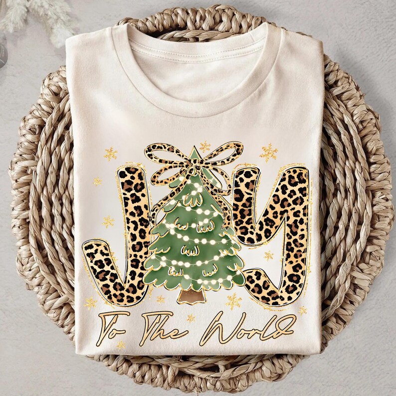 A white t-shirt with a Christmas tree design and leopard print letters, along with the text "To the World" printed on it.