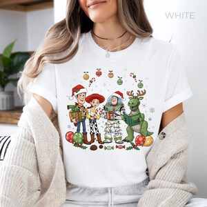 A woman wearing a white t-shirt with a Christmas-themed graphic design featuring characters from the Toy Story franchise.