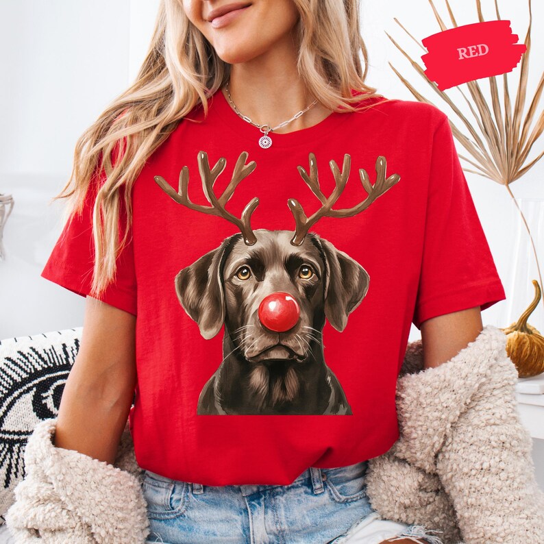 A woman wearing a red t-shirt with a graphic of a dog wearing antlers and a red nose, which appears to be a Christmas-themed design.