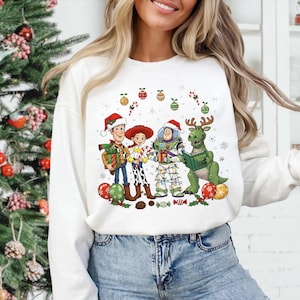 A woman wearing a white sweater with a Christmas-themed graphic design featuring characters from the Toy Story franchise.