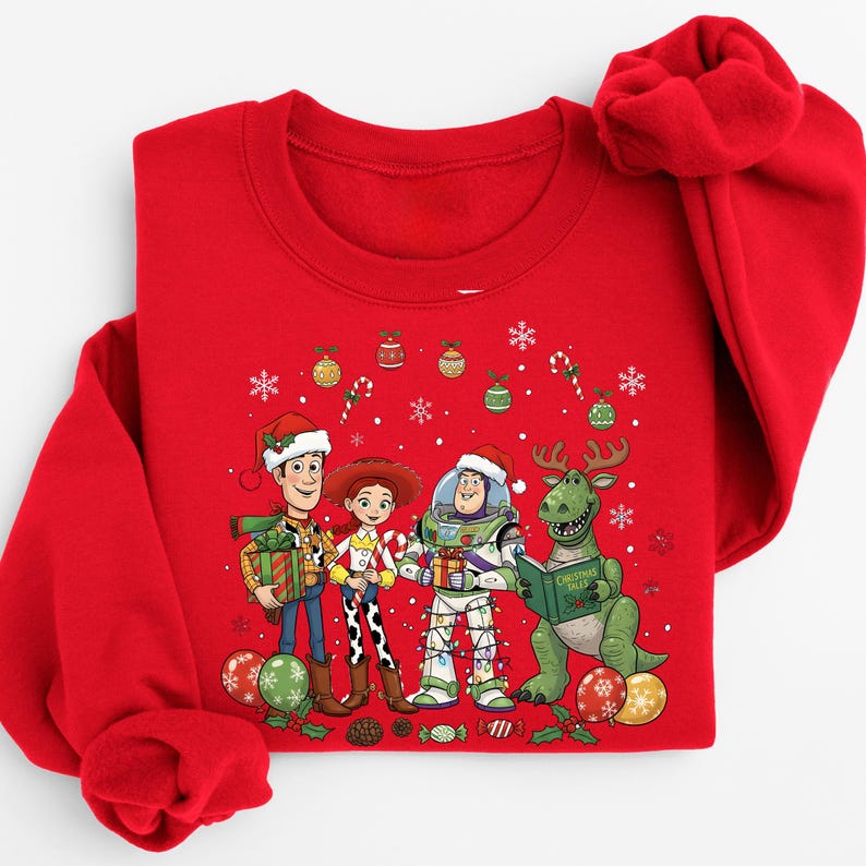 A red long-sleeved shirt with a Christmas-themed design featuring characters from the Toy Story franchise, including Woody, Buzz Lightyear, and a dinosaur.