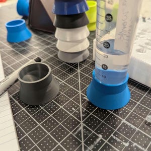 Könnte beinhalten: Eine Sammlung von 3D-gedruckten Laborgeräten, darunter Messzylinder und Trichter. Die Trichter sind in verschiedenen Farben erhältlich: Blau, Schwarz, Weiß und Grau. Ein Messzylinder ist mit einer klaren Flüssigkeit gefüllt.