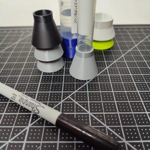 May include: An assortment of laboratory equipment, including graduated cylinders, funnels, and a Sharpie marker. The cylinders are clear with blue and white accents, and the funnels are gray and black. The Sharpie is white with a black tip.