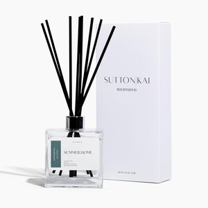 May include: A clear glass reed diffuser with black reeds and a white box. The diffuser has a label that reads "SUMMER HOME" and "SUTTONKAI". The box is white with the text "SUTTONKAI REED DIFFUSER OIL".