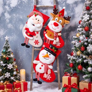 May include: Three Christmas stockings featuring plush appliqués of Santa Claus, a reindeer, and a snowman. Each stocking is red and white with striped accents, hanging from a wooden ladder. The Santa has a striped hat, the reindeer has antlers and a scarf, and the snowman wears a black top hat and a striped scarf.