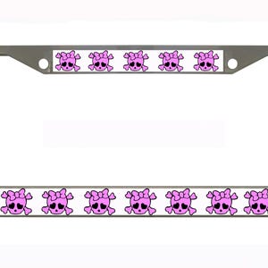 Puede incluir: Un marco de matrícula plateado con un borde blanco que presenta un patrón repetido de calaveras rosas con lazos. Las calaveras tienen ojos negros y están sobre un fondo blanco.