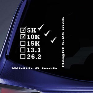 May include: White vinyl decal with text and checkmarks. The decal includes checkboxes for 5K, 10K, 15K, 13.1, and 26.2, with checkmarks next to 5K and 10K. The decal is 6 inches wide and 5.25 inches high.