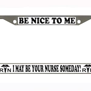May include: A silver license plate frame with the text "BE NICE TO ME" at the top and "I MAY BE YOUR NURSE SOMEDAY! RN" at the bottom. The text is in black on a white background.