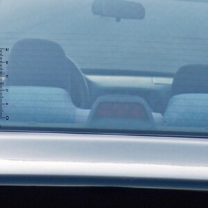 May include: Pink vinyl car decal with the words "Bite Me" and a fishing hook design. The decal is applied to the rear window of a car. The text and hook are in a cursive font.