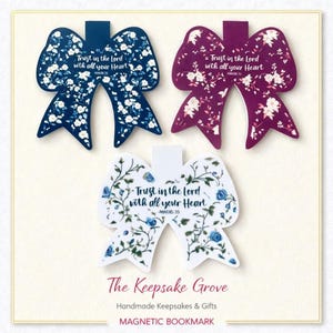 May include: Three bow-shaped magnetic bookmarks with floral patterns. One is navy blue with white flowers, another is burgundy with white flowers, and the third is white with blue flowers. Each bookmark has the text "Trust in the Lord with all your Heart".