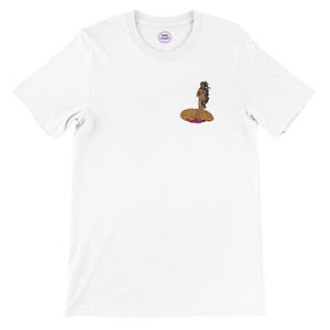 Op de afbeelding: Wit T-shirt met een kleine afbeelding van een persoon met lang haar zittend op een luipaardprint ontwerp. Het shirt heeft een ronde hals en korte mouwen. Een klein rond logo met de tekst "GIRL STUFF" staat linksboven.
